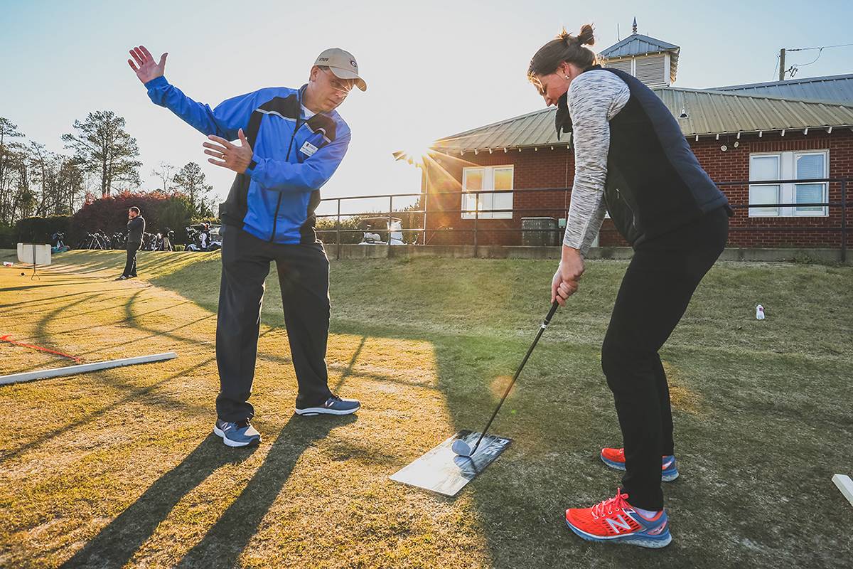 A woman gets instruction on her swing at the range from Matt Peterson.