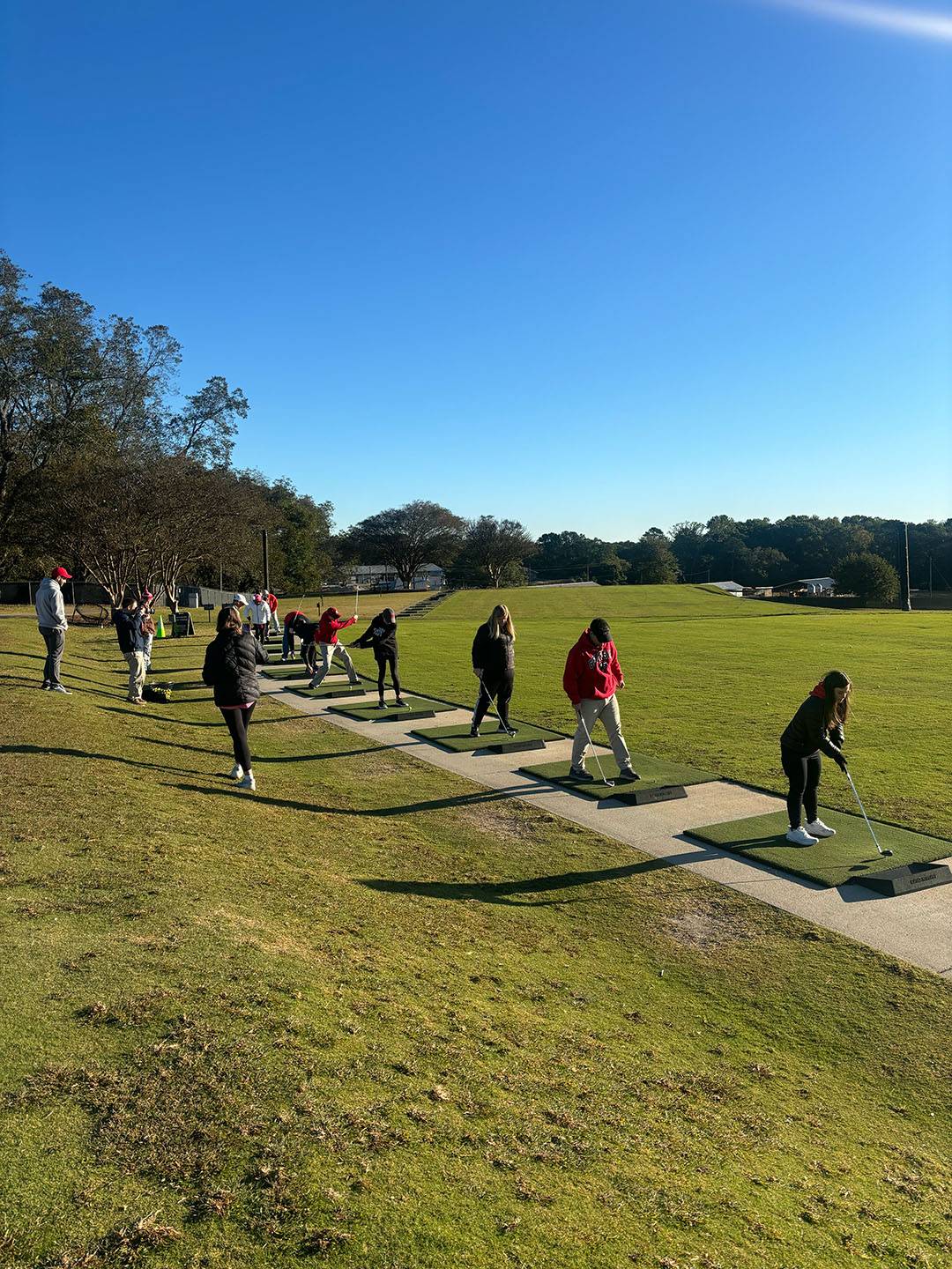 A photograph of people at the driving range.